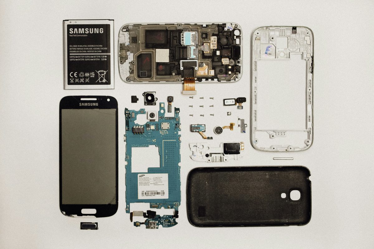Smartphone entièrement démonté montrant tous ses composants étalés : batterie, écran, carte mère, appareils photo, haut-parleur, châssis et coque